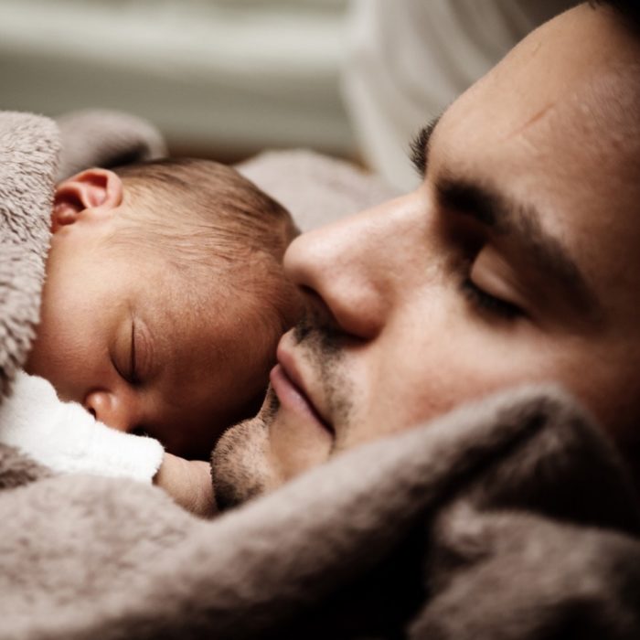 A resting man holds his infant child.