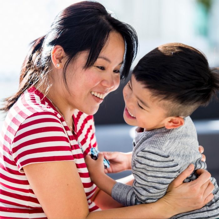 A woman laughs with her toddler son.