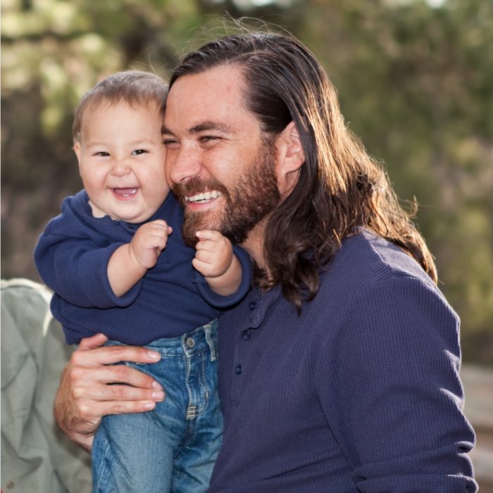 A man hugs his laughing child.